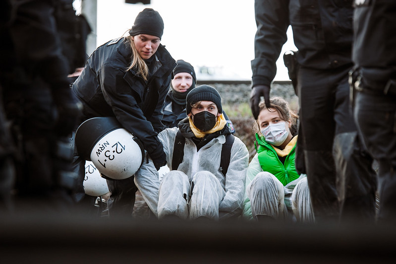 Aktivisti werden von Cops aus ihrer Sitzblockade geräumt. 